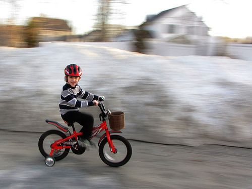Kid rides bycicle with helmet.
