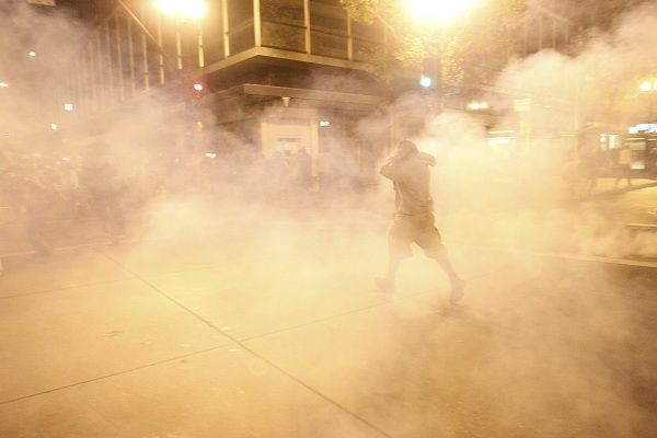 A masked Occupy Wall St. demonstrator walks away as authorities deploy tear gas during an demonstration in response to an early morning police raid which displaced Occupy Oakland's tent city in Oakland, California October 25, 2011.