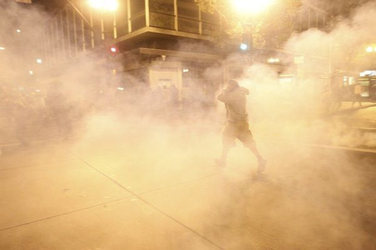 A masked Occupy Wall St. demonstrator walks away as authorities deploy tear gas during an demonstration in response to an early morning police raid which displaced Occupy Oakland's tent city in Oakland, California October 25, 2011.