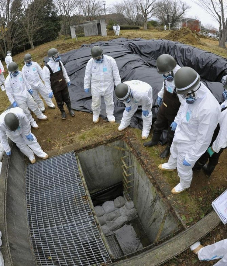 Members of Japan's Ground Self-Defense Force wearing protective suits look at a drainage channel as they decontaminate areas tainted with radioactive substances from the Fukushima Daiichi Nuclear Power plant near the Tomioka town hall in Tomioka town, Fuk