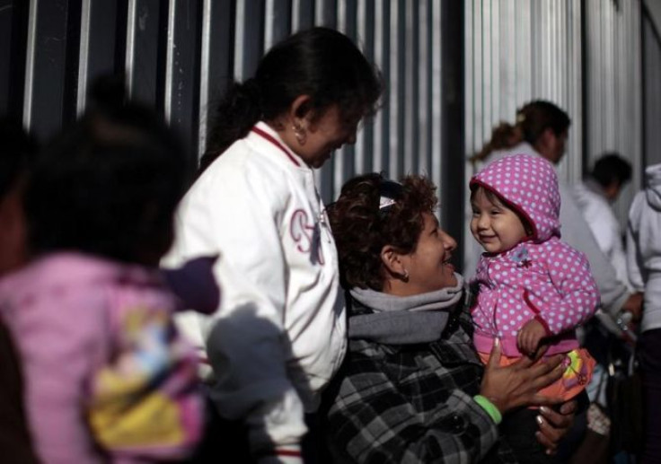 Carla Arias, 32, (2nd R) holds her eight-month-old daughter Dana Arias as they wait to go into a "Back-to-School" giveaway at the Fred Jordan Mission in Los Angeles, California October 6, 2011.