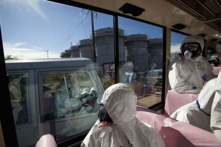 Officials from the Tokyo Electric Power Co. and journalists look out from bus windows as workers pass by in a van inside the grounds of the crippled Fukushima Daiichi nuclear power plant in Fukushima prefecture, November 12, 2011. Conditions at Japan's wr