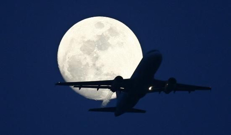 A passenger aircraft is silhouetted against the rising moon in New Delhi May 7, 2009.