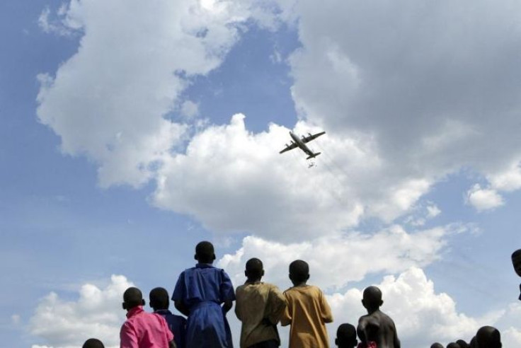 Internally displaced children look at a UN World Food Programme (WFP) plane air dropping food in Olilim.
