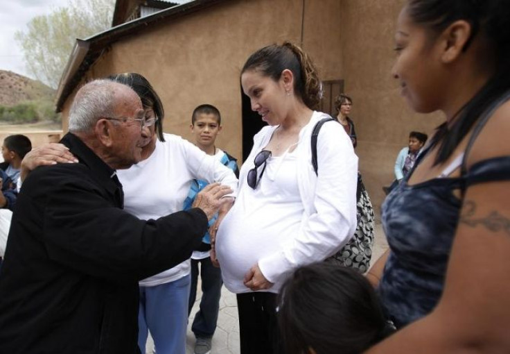 Father Casimiro Roca, (L), blesses the belly of a pregnant woman after Easter mass outside of El Santuario de Chimayo in Chimayo, New Mexico April 24, 2011.