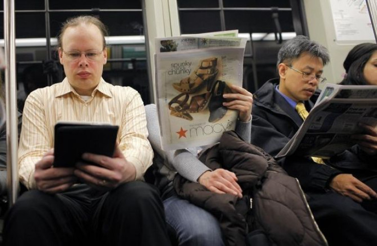 A commuter (L) reads on a Kindle e-reader while riding the subway in Cambridge, Massachusetts March 18, 2011.