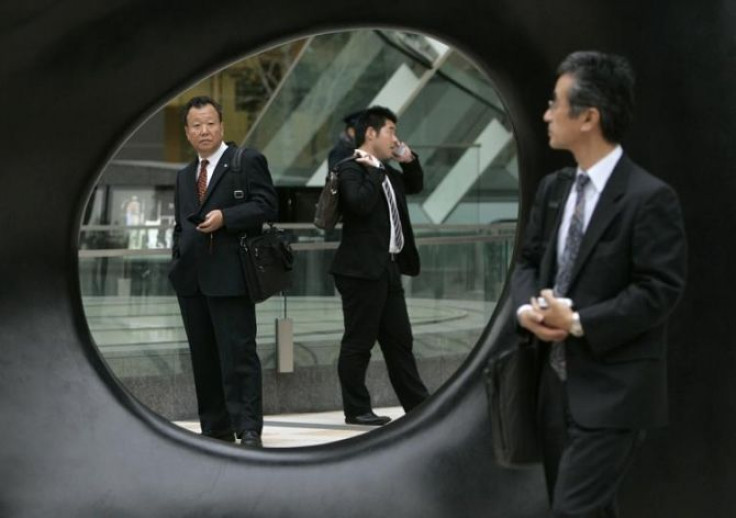 A businessman (R) glances at other men through a work of outdoor art in Tokyo