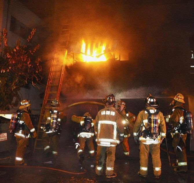 Firefighters try to put out an apartment fire that started from one of the 12 new carport fires set by an arsonist early Monday morning, in West Hollywood, California January 2, 2012.