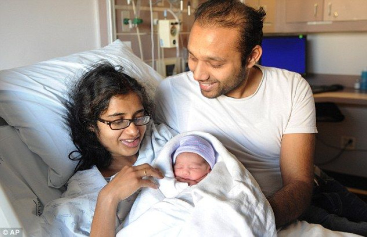 A New Jersey couple poses for a photo with their baby boy who was born on the PATH train from New Jersey to New York.