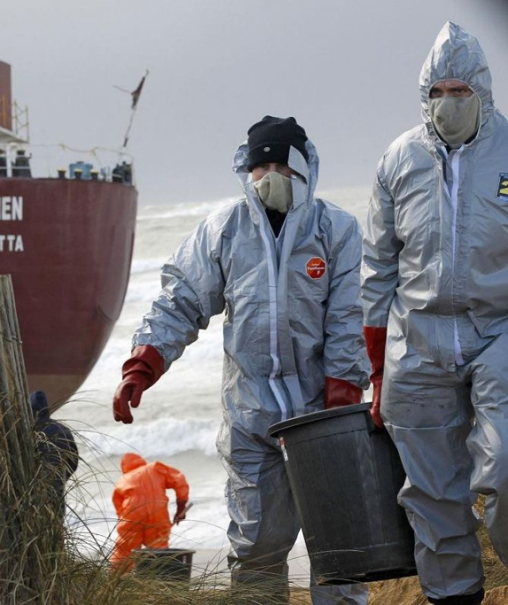 Workers clean the beach after the Maltese-registered cargo ship the TK Bremen ran aground on Kerminihy beach at Erdeven, spilling oil from its engines on the coast of Brittany in western France, December 16, 2011.