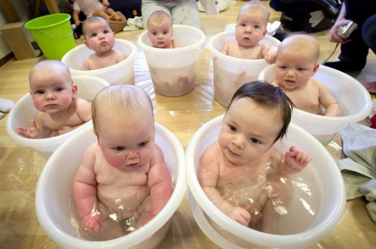 Seven babies sit in tummy tubs filled with water to cool down after a baby massage class held for young mothers in IJmuiden