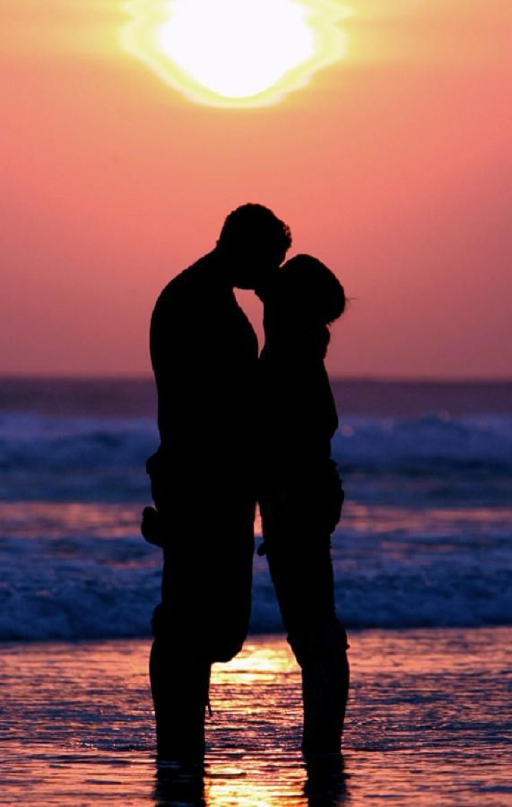 Western tourists kiss during sunset near Kuta beach