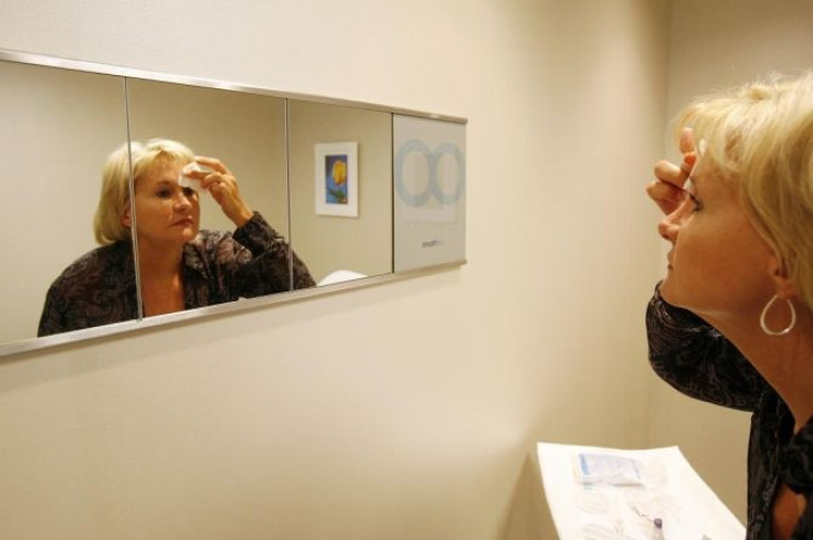 A woman looks at herself in a mirror after receiving a Botox injection at a walk-in Botox salon