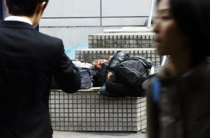 A homeless man takes a nap as people walk past in Tokyo March 31, 2009.