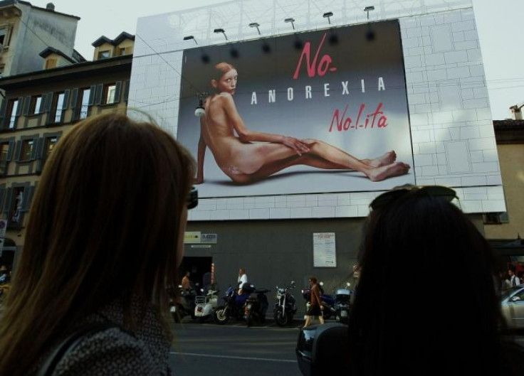 Two women look at an advertising board showing a shockingly emaciated naked woman in Milan September 24, 2007.