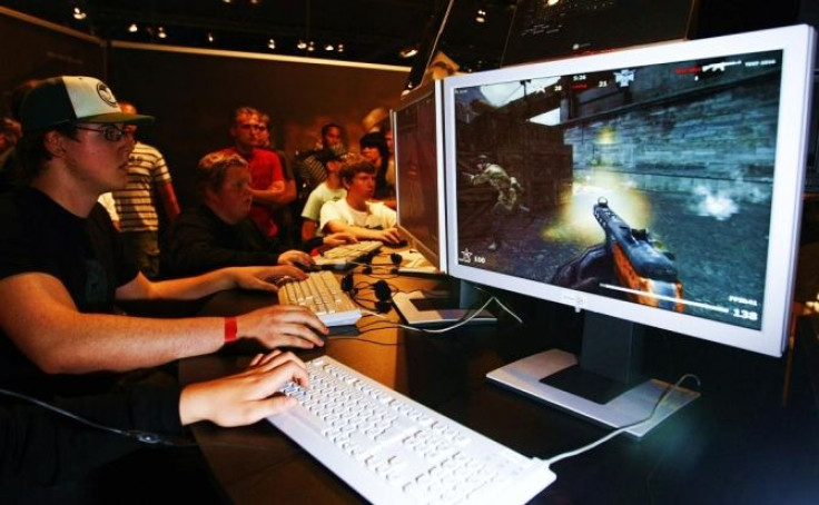 Visitors play the game &quot;Karma&quot; at an exhibition stand at the Games Convention Online 2009 fair in Leipzig