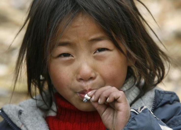 A child from the Yi ethnic minority smokes a cigarette at Dayingpan Village in Yuexi County, China.