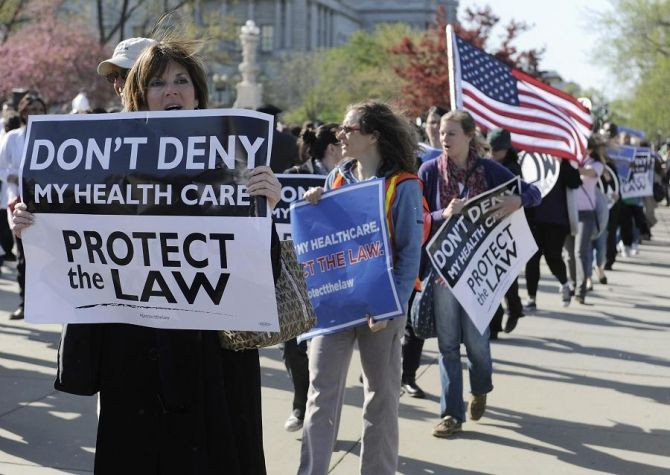 People rally on the sidewalk as legal arguments over the Patient Protection and Affordable Care Act take place at the Supreme Court.