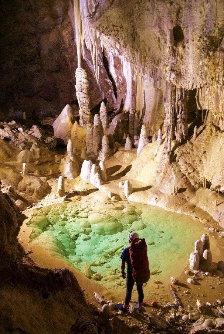 A researcher at 'Pearlsian Gulf' in Lechuguilla Cave, calcite formations are in the background.