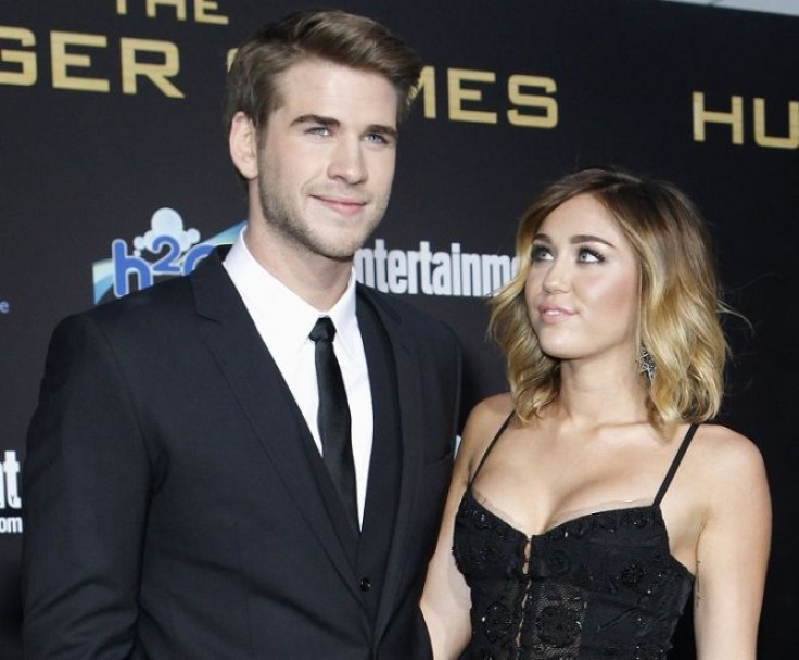 Cast member Liam Hemsworth poses with actress Miley Cyrus at the premiere of &quot;The Hunger Games&quot; at Nokia theatre in Los Angeles, California March 12, 2012.