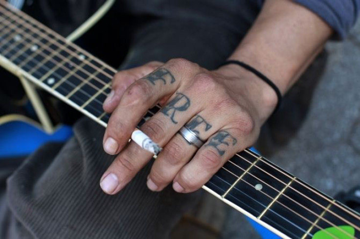 An Occupy Wall Street activist with the word "Free" tattooed on his hand plays a guitar during a May Day demonstration in New York May 1, 2012.