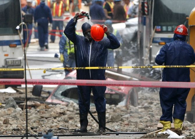 A worker wearing Hazmat suit cleans himself off with a hose at the site of a steam pipe explosion in New York