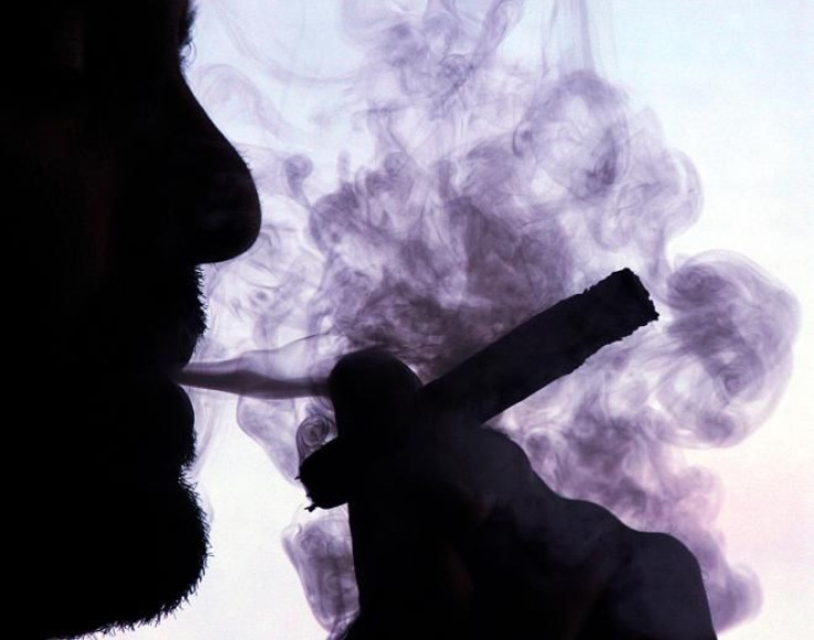 A man smokes a cigar while standing next to a window in Havana, January 20, 2005.