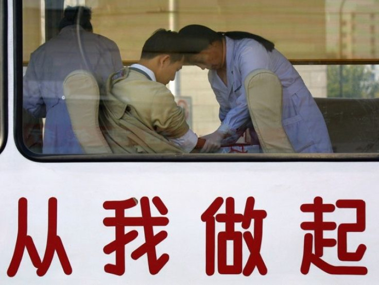 A Chinese man donates blood at a government-run mobile donation centre decorated with Chinese characters which read &quot;Start From Me&quot; in Beijing November 18, 2001.