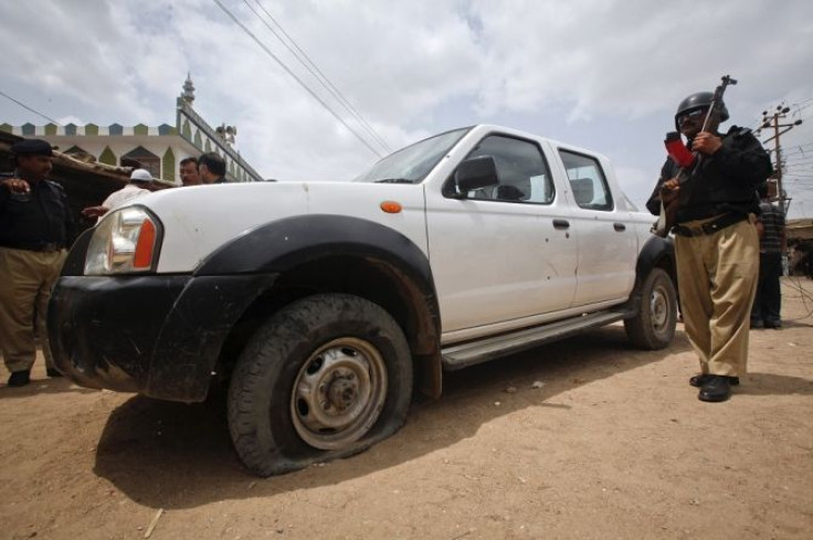 A policeman stands guard near a vehicle that was attacked by unidentified gunmen in Gadap Town, Karachi July 17, 2012. Gunmen in Pakistan shot and wounded a staff member of the World Health Organization (WHO) and an expatriate consultant working for the U
