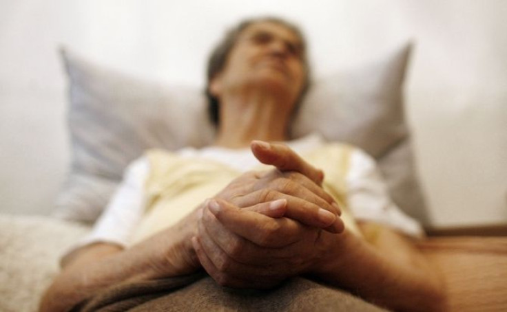 Alzheimer's disease patient sits in an armchair in her house.