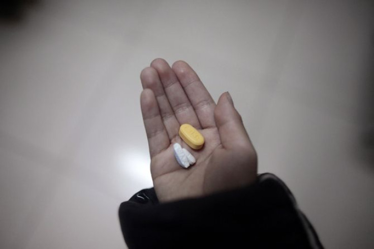 HIV infected boy Gao Jun, 8, holds in his hands antiretroviral drugs used in the treatment of HIV, in an orphanage run by the Fuyang AIDS Orphan Salvation Association in Fuyang, Anhui province November 27, 2009.