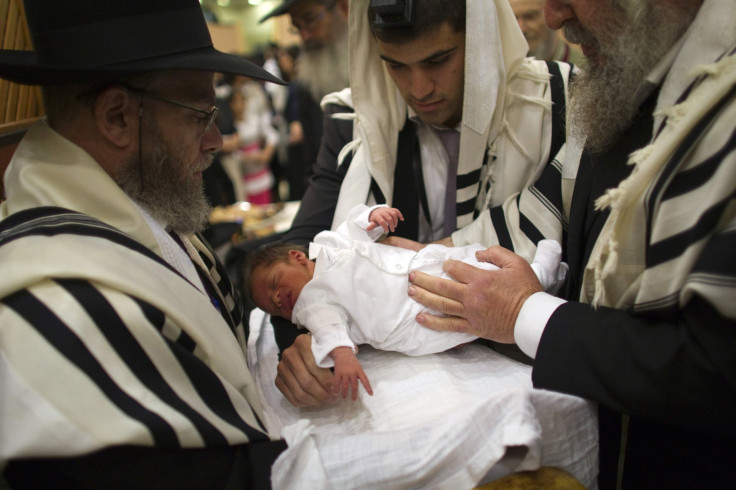 Ultra-Orthodox Jewish father holds his son before his circumcision.
