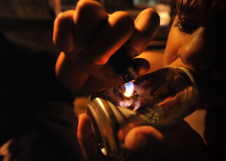 A woman smoking crack cocaine out of a can.