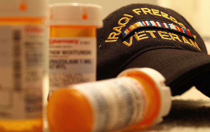 Pill bottles next to an Iraqi Freedom veteran hat.