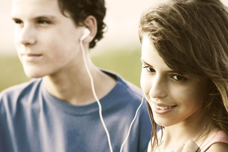 Teens sharing headphones