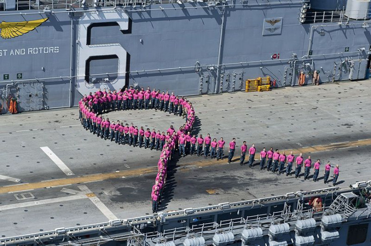 Sailors stand in a pink ribbon formation at sea