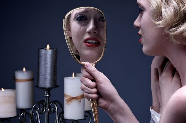 Crying woman looking into mirror 