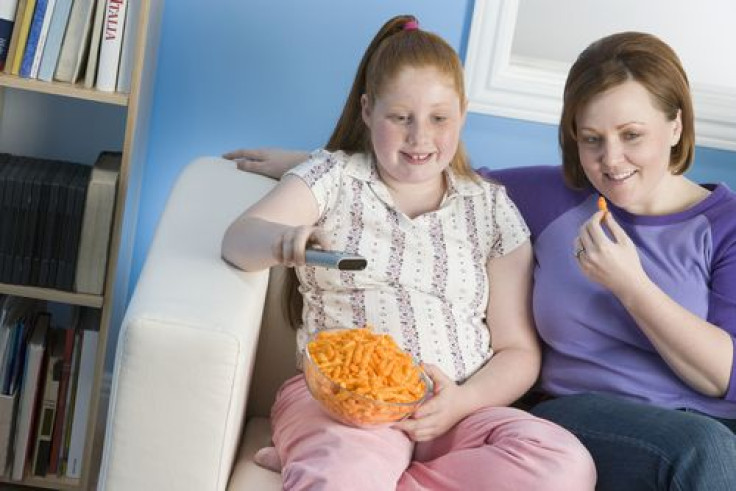 Mother and daughter watching TV with food