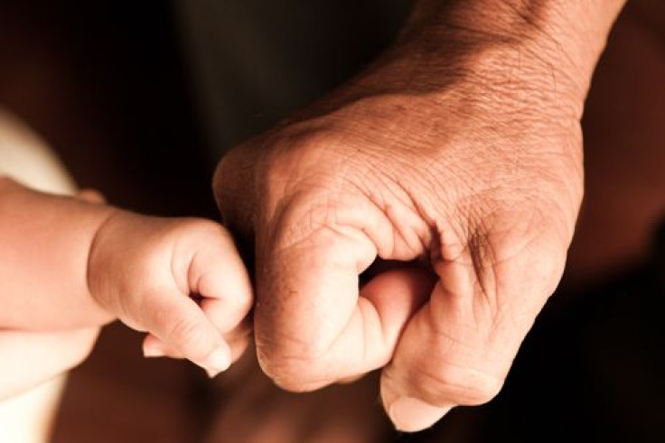 A baby hand and adult hand fist bumping