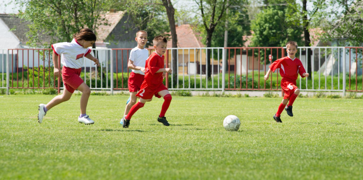 Boy kicking ball via shutterstock