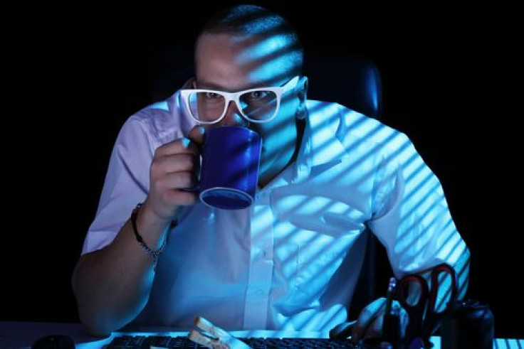 Night shift worker in front staring at computer screen while drinking coffee