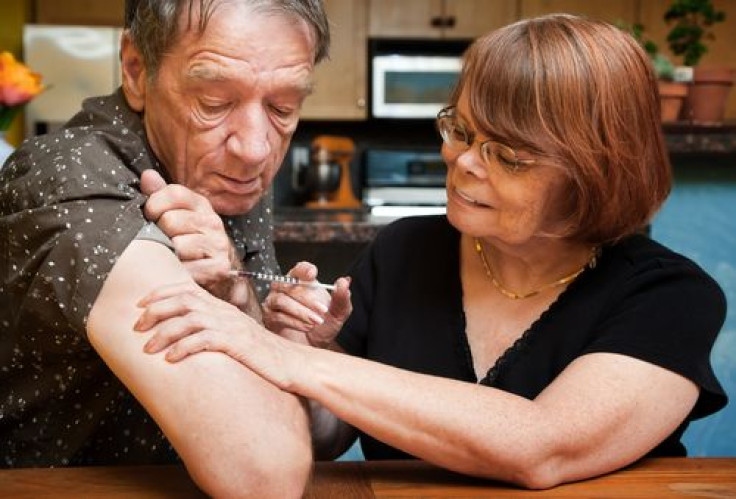 Woman giving man shot with small hypodermic needle