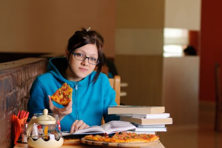 College student eating pizza and studying