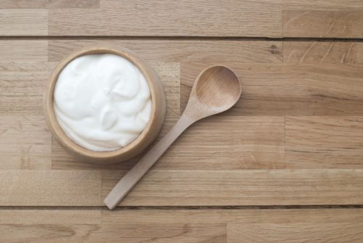 Greek yogurt in wood bowl next to wood spoon