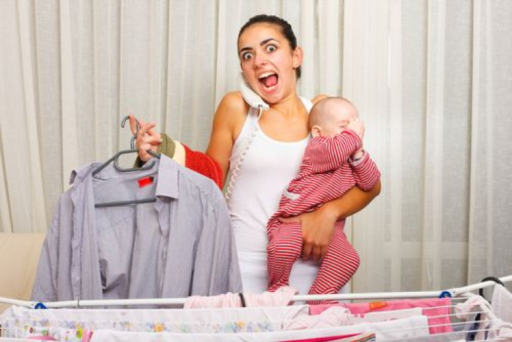 Mother stressed while doing laundry and holding her crying infant while talking on the phone