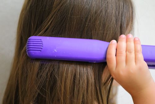 Young girl straightening her hair