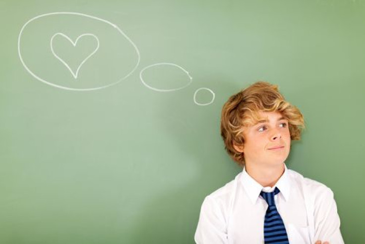 Boy thinking about love next to chalkboard 