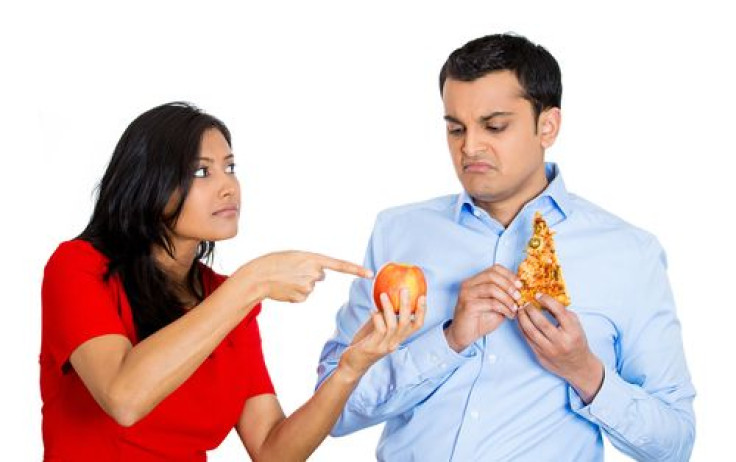 Woman convincing man to eat fruit instead of pizza