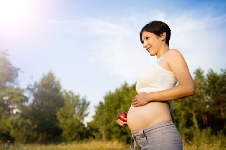 Pregnant woman outside with apple