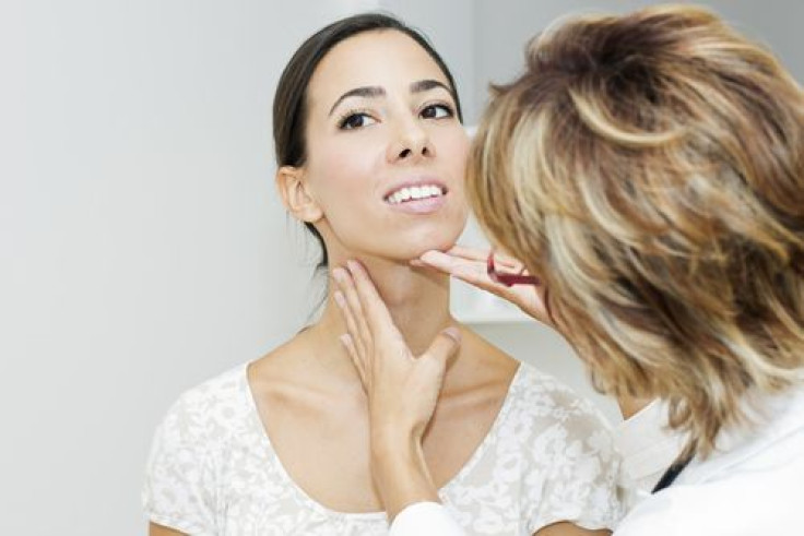 Doctor examining female patient's thyroid 